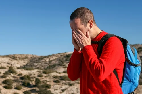 A hiker experiencing Altitude Sickness while trekking at high altitude, showing symptoms such as headache and fatigue in a mountainous landscape.